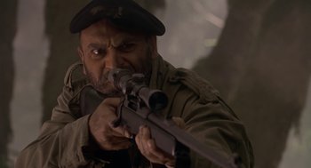 Movie still from “Harry and the Hendersons” (1987), directed by William Dear – A man with a gun in his hands; Close Up shot, Low angle