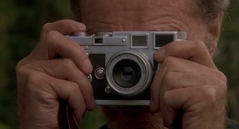 Movie still from “Harry and the Hendersons” (1987), directed by William Dear – A man holding a camera up to his face; Extreme Close Up shot, Low angle