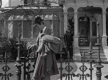 Movie still from “Harvey” (1950), directed by Henry Koster – A man walking in front of a house with a hat on; Wide shot, Low angle