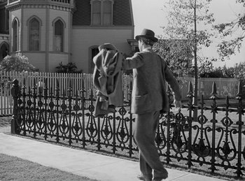 Movie still from “Harvey” (1950), directed by Henry Koster – A man in a suit and a hat walking down the street; Wide shot, Low angle