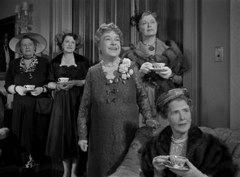 Movie still from “Harvey” (1950), directed by Henry Koster – A black and white photo of a group of women holding tea cups; Medium shot, High angle