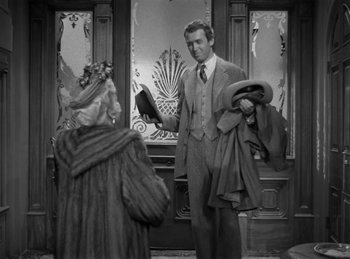 Movie still from “Harvey” (1950), directed by Henry Koster – A black and white photo of a man and a woman in front of a door; Medium shot, Over the shoulder angle