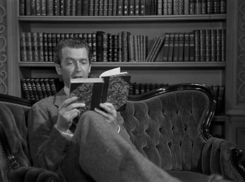 Movie still from “Harvey” (1950), directed by Henry Koster – A man sitting in a chair reading a book; Medium shot, High angle