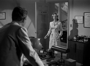 Movie still from “Harvey” (1950), directed by Henry Koster – A woman standing in front of a mirror in a room; Medium shot, Over the shoulder angle