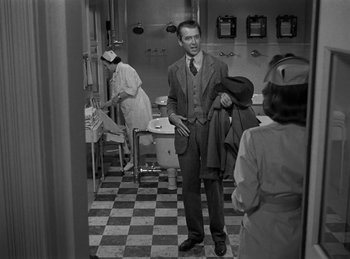 Movie still from “Harvey” (1950), directed by Henry Koster – A man standing in a room holding a jacket; Medium shot, Over the shoulder angle