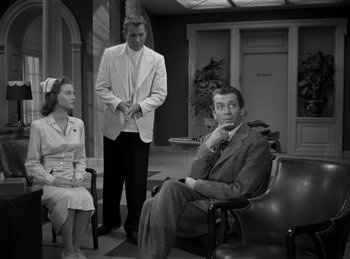 Movie still from “Harvey” (1950), directed by Henry Koster – A black and white photo of a man and a woman and another man; Medium shot, Over the shoulder angle