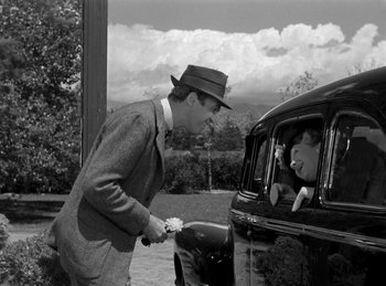 Movie still from “Harvey” (1950), directed by Henry Koster – A black and white photo of a man and a woman in the back of a car; Wide shot, Low angle