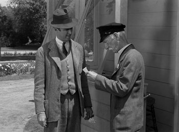 Movie still from “Harvey” (1950), directed by Henry Koster – Two men standing next to each other and one of the men is holding a piece of paper in his hand; Medium shot, Over the shoulder angle