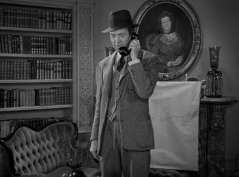 Movie still from “Harvey” (1950), directed by Henry Koster – A man talking on a phone while wearing a suit and hat; Medium shot, High angle