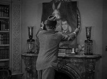 Movie still from “Harvey” (1950), directed by Henry Koster – A man in a suit and a hat standing in front of a painting; Medium shot, Over the shoulder angle