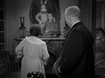 Movie still from “Harvey” (1950), directed by Henry Koster – A man and a woman standing in front of a fireplace; Medium shot, Over the shoulder angle