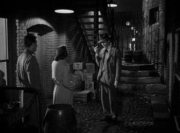 Movie still from “Harvey” (1950), directed by Henry Koster – An old photo of a man and two women talking to each other; Wide shot, Over the shoulder angle