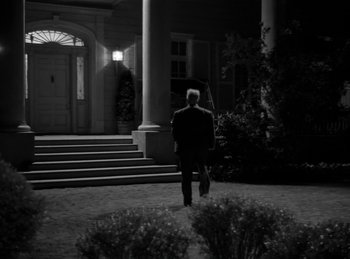 Movie still from “Harvey” (1950), directed by Henry Koster – A man in a suit walking in front of a building; Wide shot, Low angle