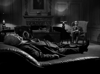 Movie still from “Harvey” (1950), directed by Henry Koster – A man laying on a couch next to a man sitting in a chair; Wide shot, High angle
