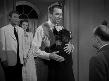 Movie still from “Harvey” (1950), directed by Henry Koster – An old photo of a man hugging a woman in front of other people; Medium shot, Over the shoulder angle