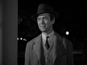 Movie still from “Harvey” (1950), directed by Henry Koster – A black and white photo of a man wearing a suit and a hat; Medium shot, Over the shoulder angle