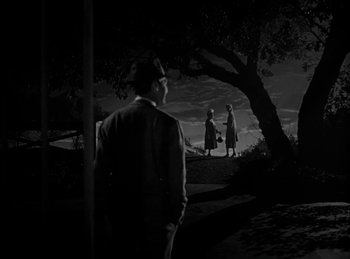 Movie still from “Harvey” (1950), directed by Henry Koster – A man and two women standing under a tree; Extreme Wide shot, Low angle