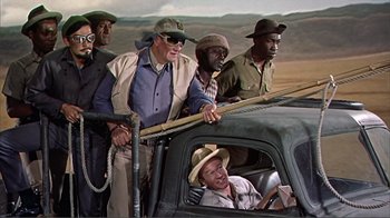 Movie still from “Hatari!” (1962), directed by Howard Hawks – A group of men standing in the back of a truck; Wide shot, Low angle