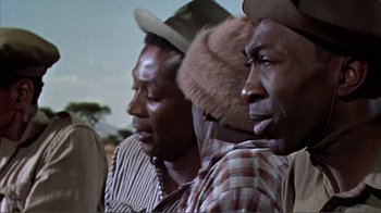 Movie still from “Hatari!” (1962), directed by Howard Hawks – A group of men standing next to each other wearing hats; Close Up shot, Low angle