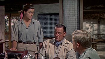 Movie still from “Hatari!” (1962), directed by Howard Hawks – A group of people sitting around a table; Medium shot, Over the shoulder angle