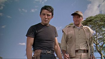 Movie still from “Hatari!” (1962), directed by Howard Hawks – A man and a man standing next to each other; Medium shot, Low angle