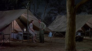 Movie still from “Hatari!” (1962), directed by Howard Hawks – A man and a woman sitting in front of a tent; Wide shot, High angle