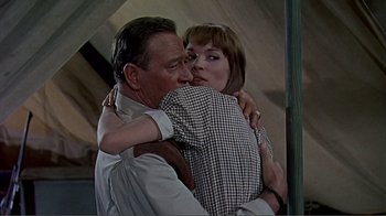 Movie still from “Hatari!” (1962), directed by Howard Hawks – An older man hugging a young woman in a room; Medium shot, Low angle