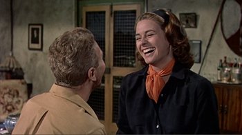 Movie still from “Hatari!” (1962), directed by Howard Hawks – A man and a woman laughing together in front of a building; Medium shot, Over the shoulder angle