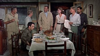 Movie still from “Hatari!” (1962), directed by Howard Hawks – A group of people standing around a table with food on top of it; Wide shot, High angle