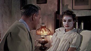 Movie still from “Hatari!” (1962), directed by Howard Hawks – A man and a woman are talking in front of a lamp; Medium shot, Over the shoulder angle