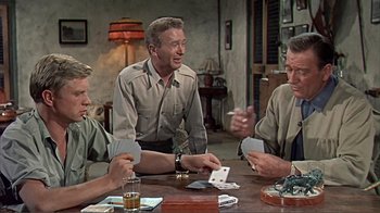 Movie still from “Hatari!” (1962), directed by Howard Hawks – A group of men sitting at a table playing cards; Medium shot, Over the shoulder angle