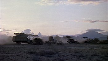 Movie still from “Hatari!” (1962), directed by Howard Hawks – A group of trucks driving down a dirt road; Extreme Wide shot, Low angle