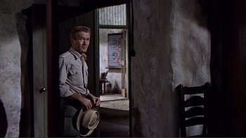 Movie still from “Hatari!” (1962), directed by Howard Hawks – A man standing in front of an open door; Medium shot, Over the shoulder angle
