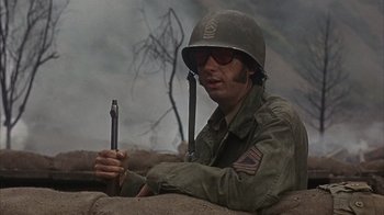 Movie still from “Head” (1968), directed by Bob Rafelson – A man in a military uniform holding a rifle; Close Up shot, Low angle
