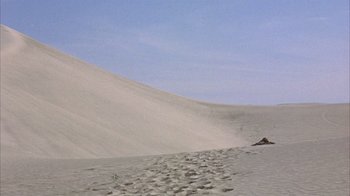 Movie still from “Head” (1968), directed by Bob Rafelson – A sand dune with a sky filled with clouds; Extreme Wide shot, Low angle