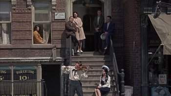 Movie still from “Head” (1968), directed by Bob Rafelson – A group of people standing on steps in front of a brick building; Wide shot, High angle