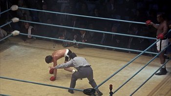 Movie still from “Head” (1968), directed by Bob Rafelson – Two men in a boxing ring with spectators in the background; Wide shot, High angle