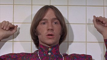 Movie still from “Head” (1968), directed by Bob Rafelson – A man with long brown hair wearing a colorful shirt; Close Up shot, Low angle