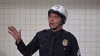 Movie still from “Head” (1968), directed by Bob Rafelson – A man in a police uniform wearing a helmet; Close Up shot, Over the shoulder angle