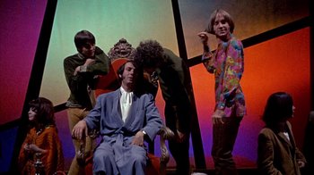 Movie still from “Head” (1968), directed by Bob Rafelson – A group of people standing next to each other on a stage; Medium shot, High angle