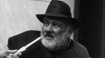 Movie still from “Head” (1968), directed by Bob Rafelson – An older man with a beard and a hat smoking a pipe; Close Up shot, Low angle