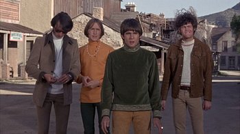Movie still from “Head” (1968), directed by Bob Rafelson – A group of young men standing next to each other on a street; Medium shot, Low angle