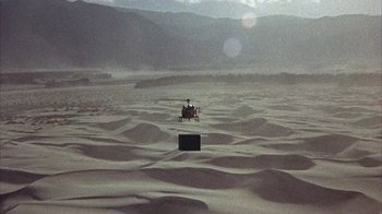 Movie still from “Head” (1968), directed by Bob Rafelson – A helicopter is flying over the sand dunes in the desert; Extreme Wide shot, High angle