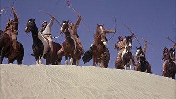 Movie still from “Head” (1968), directed by Bob Rafelson – A group of people riding on the backs of horses; Wide shot, Low angle