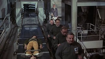 Movie still from “Head” (1968), directed by Bob Rafelson – A group of men walking down a conveyor belt; Wide shot, High angle