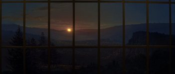 Movie still from “Heartbeeps” (1981), directed by Allan Arkush – The sun is setting over a mountain range through a window; Extreme Wide shot, Low angle