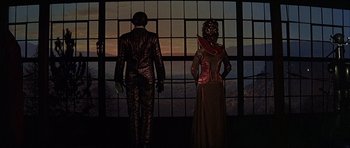 Movie still from “Heartbeeps” (1981), directed by Allan Arkush – A couple of people standing in front of a window; Wide shot, Low angle