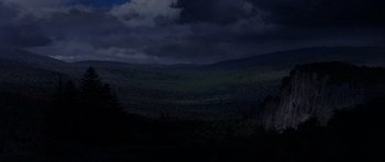 Movie still from “Heartbeeps” (1981), directed by Allan Arkush – A view of a mountain range at night with dark clouds in the background; Extreme Wide shot, High angle