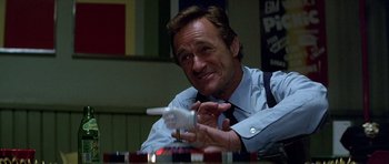 Movie still from “Heartbeeps” (1981), directed by Allan Arkush – A man sitting at a table holding a remote control; Close Up shot, High angle