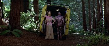 Movie still from “Heartbeeps” (1981), directed by Allan Arkush – A man and a woman dressed in costumes standing in front of a bus; Wide shot, Low angle